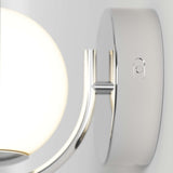 Close-up of a modern chrome wall sconce with a round frosted glass shade, mounted on a smooth circular base against a light gray background.
