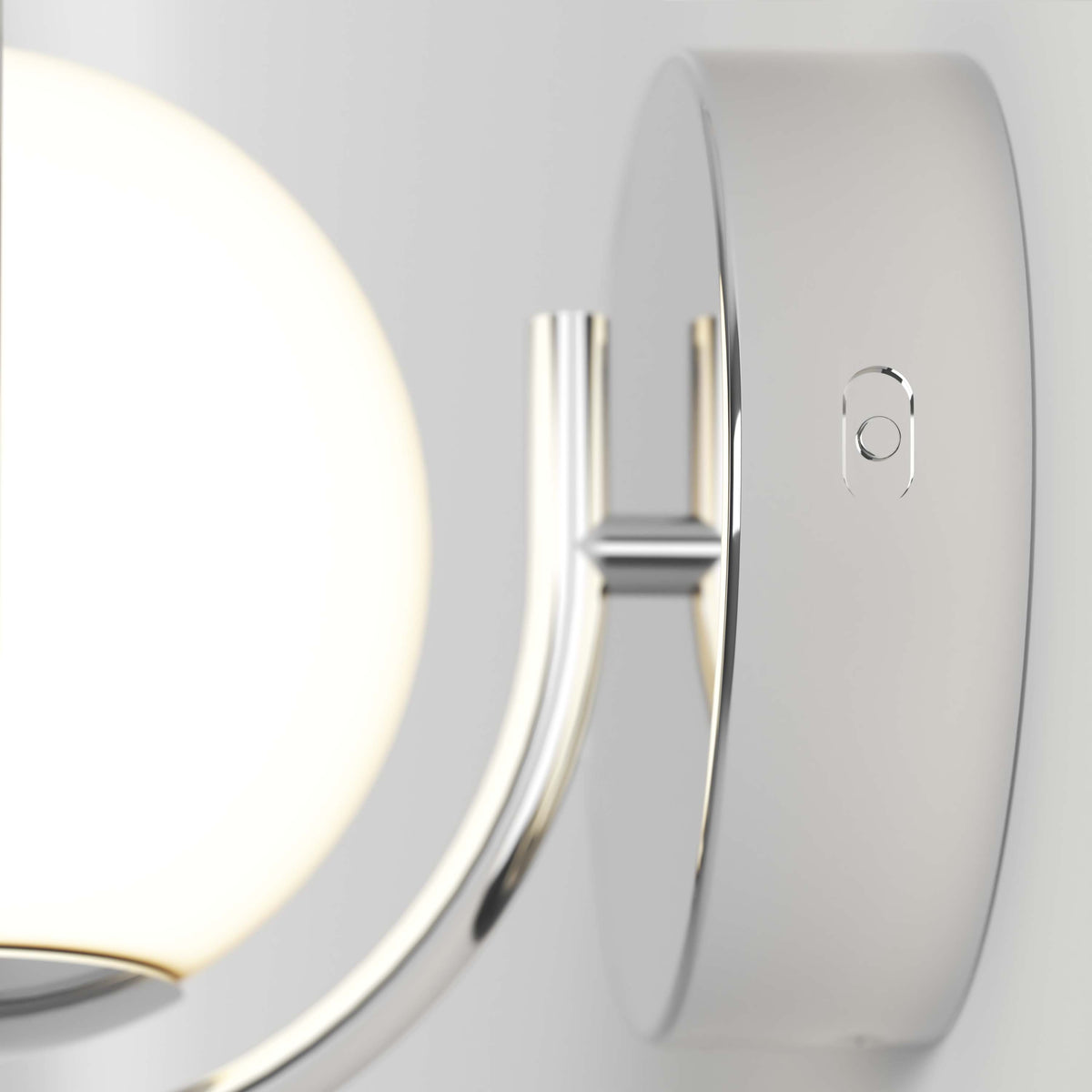 Close-up of the Artika Bloom LED Sconce 3 CCT, a modern wall-mounted fixture with a round frosted glass shade and shiny metallic base, shown on a light-colored wall.