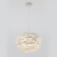 The Artika Plume LED pendant light features a spherical shade crafted from layered, feather-like white material and hangs elegantly from the ceiling by a thin cord against a plain white background.