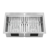 A stainless steel double-basin kitchen sink with square corners, a central faucet hole, and removable metal grids at the bottom of each basin.