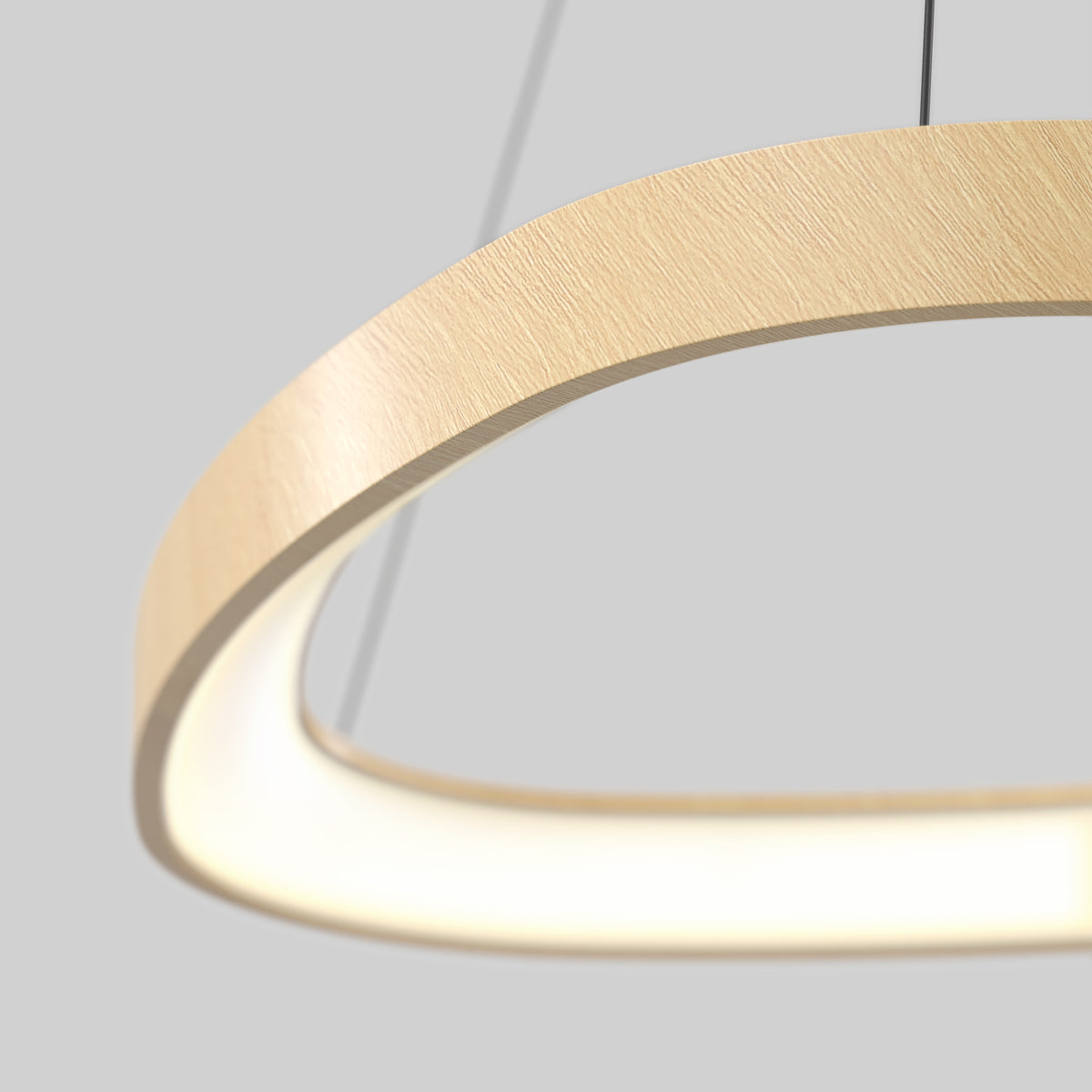 A close-up of a modern, circular wooden pendant light with a glowing ring, suspended by thin wires against a neutral gray background.