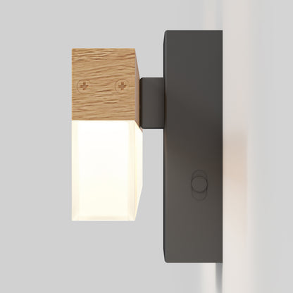 The Neil modern LED bathroom vanity light by Artika features a black rectangular base, wooden accent with plus/minus symbols, and a frosted glass shade emitting a soft glow, wall-mounted against a white background.
