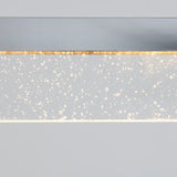 A close-up of a modern light fixture with a clear rectangular panel embedded with small bubbles, illuminated from within, against a plain gray background.