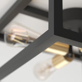 Close-up of a modern black metal light fixture with exposed light bulbs and brass sockets, set against a white ceiling background.