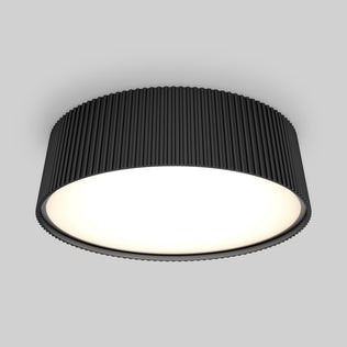 The Artika Groove 13 in. LED modern flush mount light features a black, ribbed exterior and a bright white surface, adding style to any space with its 5 CCT settings, shown installed on a light gray ceiling.