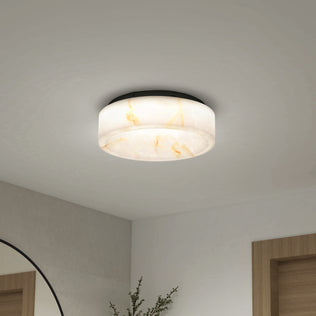 The Clifford 15 in. flush mount light by Artika, featuring a marble-patterned round design and adjustable warm glow, is installed on a white ceiling above a modern interior with a mirror, wall, and wooden door frame in view.