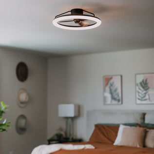 The Artika Darren 23 in. LED fandelier ceiling fan with remote brightens a cozy bedroom with wall art, hats, and a made bed.
