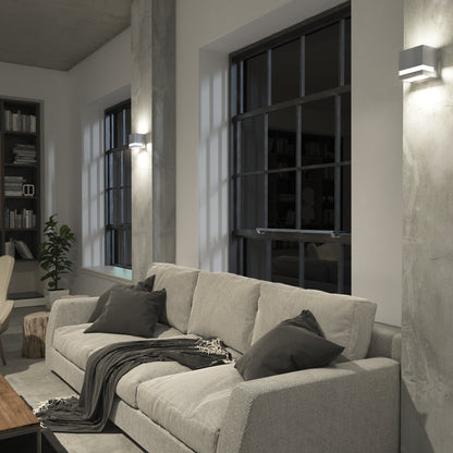 Modern living room with a light gray sofa, dark pillows, blanket, wooden coffee table, large windows, bookshelves, potted plant, and cozy minimalist decor. Features Valor Square LED wall lights by Artika-CAN-dev.