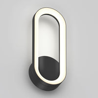 The Artika Aiden modern LED indoor-outdoor wall light 5 CCT features a black circular base and an oval LED frame, mounted vertically on a plain light gray wall.
