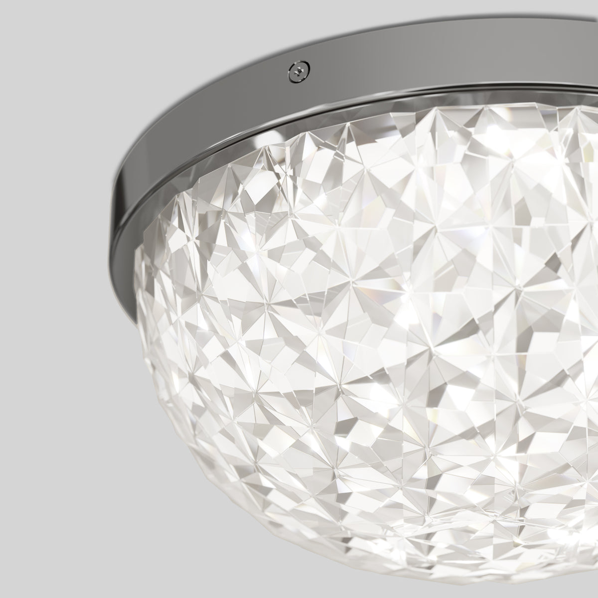 Close-up of a decorative ceiling light fixture with a faceted, clear glass dome and a shiny, metallic frame, mounted on a light gray ceiling.