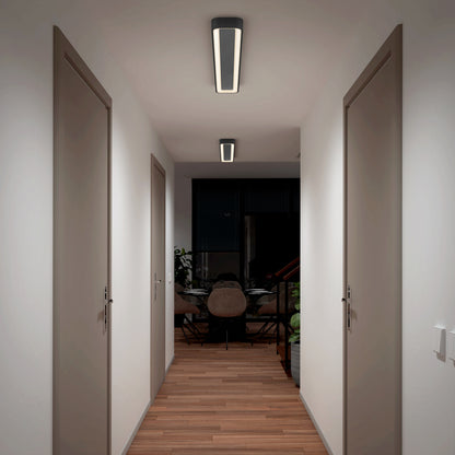 A hallway with wooden floors and white walls features the Artika Aiden 48 in. LED modern flush mount light 5 CCT on the ceiling, illuminating closed doors on both sides and a dining area with a table and chairs at the end.
