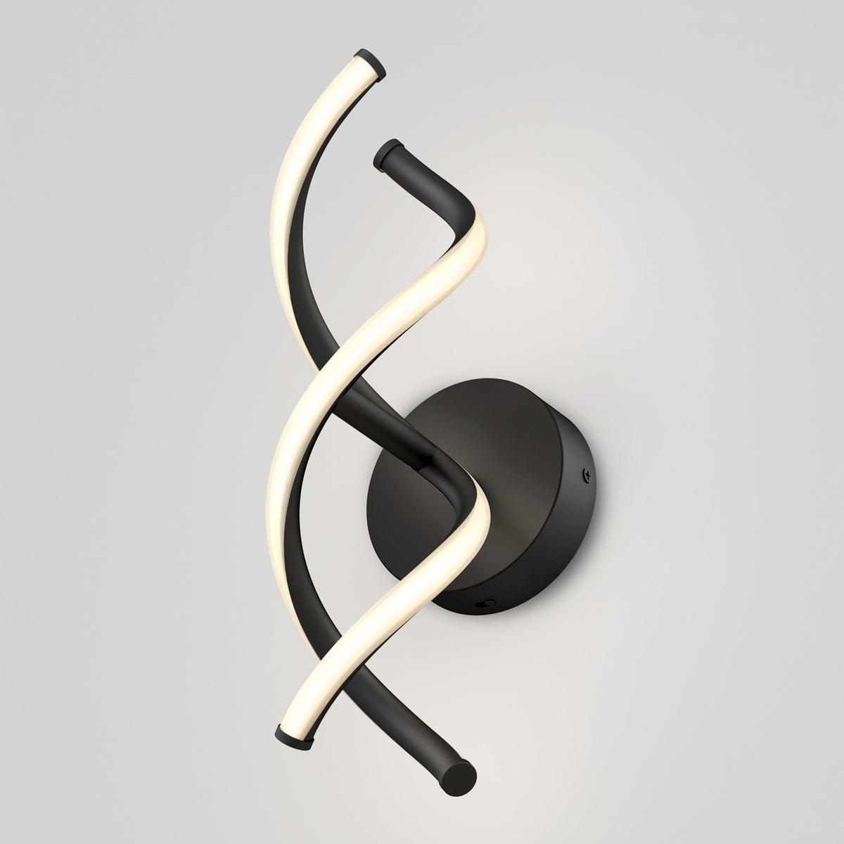 Modern wall sconce with a black circular base and two intertwined, curved light strips—one illuminated and white, the other matte black—mounted against a light gray wall.