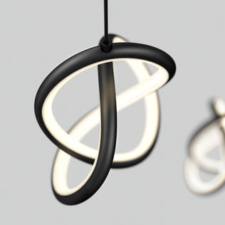The Zephyr 3-light LED pendant by Artika features intertwined black and white LED tubes suspended against a light gray background, with a second blurred fixture visible in the distance.