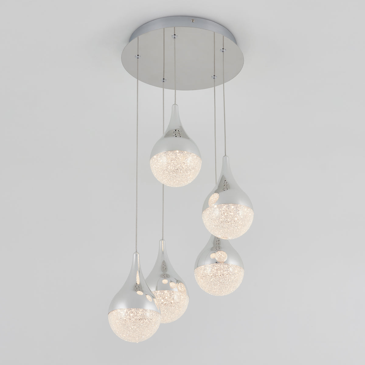 The Artika Glitzer 5-light LED pendant features five teardrop-shaped lights with silver tops and textured illuminated bottoms, each hanging at varying lengths from a round silver base for a modern ceiling accent.