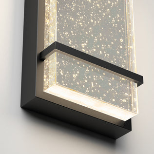 The Artika Skyler indoor-outdoor LED wall light features a modern rectangular black frame, a clear bubble-filled panel, and emits soft white illumination.