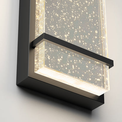 The Artika Skyler indoor-outdoor LED wall light features a modern rectangular black frame, a clear bubble-filled panel, and emits soft white illumination.