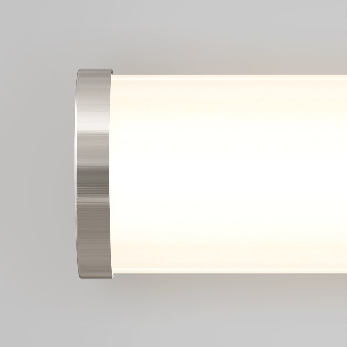 Close-up of a modern cylindrical wall light with a brushed metal end cap and a glowing frosted glass shade against a light gray background.