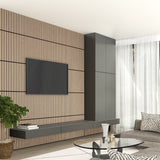 Modern living room with a wood slat accent wall, mounted flat-screen TV, floating dark gray shelves and cabinets, a round glass coffee table, gray sofa, large window with sheer curtains, and a potted plant.