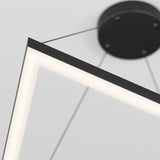 Close-up of a modern, geometric ceiling light fixture with a glowing LED edge, suspended by thin wires from a round black ceiling mount. The background is a plain white ceiling.