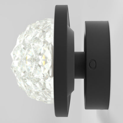 The Artika Carat LED contemporary bathroom vanity light 3 CCT features a faceted, crystal-like glass cover and a matte black circular base, ideal for modern spaces.