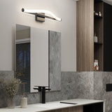 Modern bathroom with a sleek rectangular mirror, a black faucet, a light fixture with a wavy design above the mirror, wood and stone-textured walls, and shelves with various toiletries.