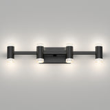 A modern wall-mounted light fixture with a rectangular base and four cylindrical lights, evenly spaced, emitting a soft white glow, set against a plain gray wall.