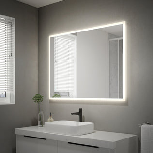A modern bathroom features gray walls, a white sink with black faucet, a Mavis 48" x 36" Rectangular LED Mirror by Artika above the countertop with drawers, a potted plant, and two windows with white blinds.
