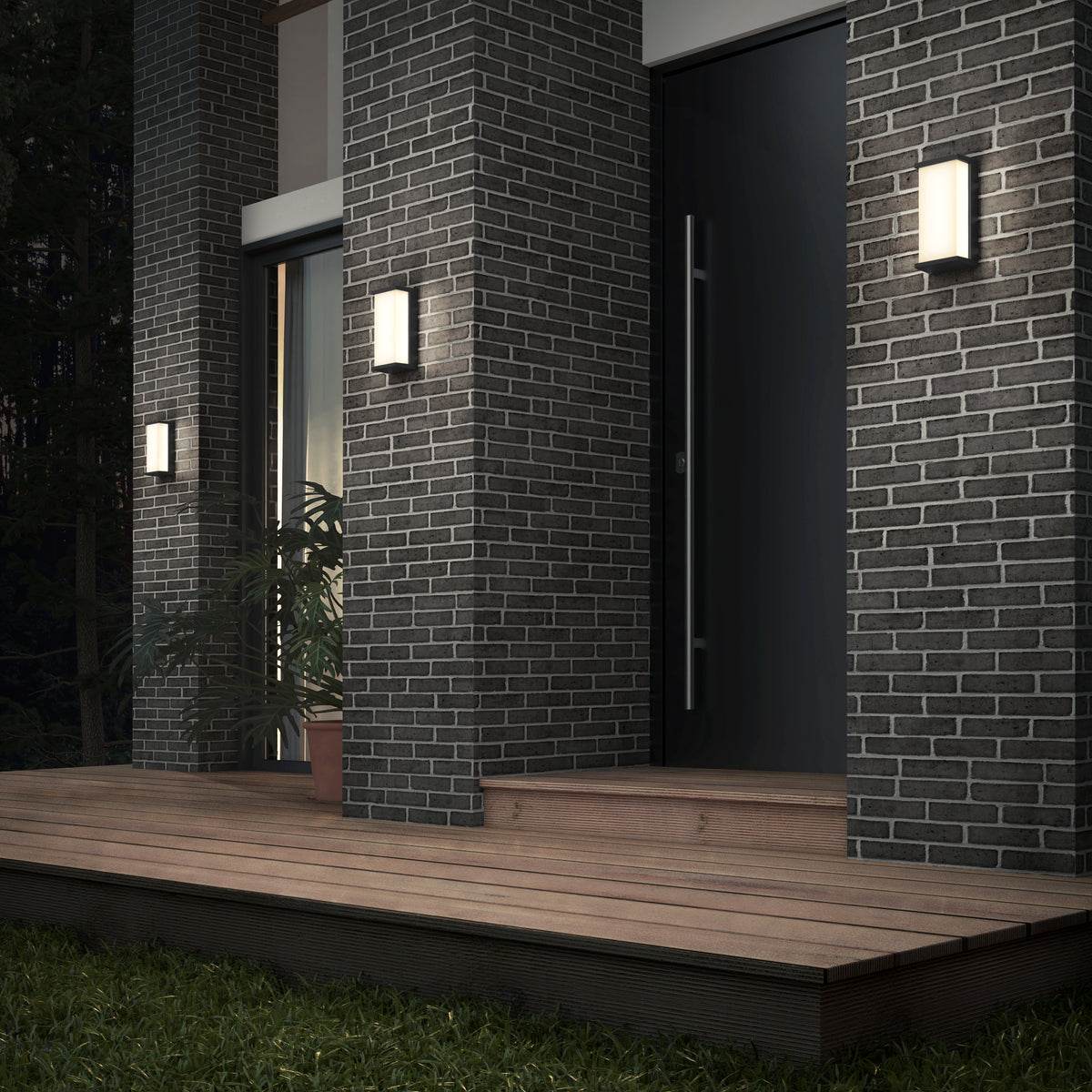 Modern house entrance with dark brick walls, a large door, wooden steps, and three illuminated rectangular wall lights. A potted plant is near the doorway, and there is greenery in the foreground.
