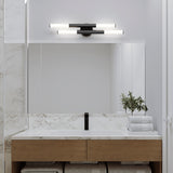 A modern bathroom with a large mirror, marble backsplash, wooden vanity, stacked white towels, a small plant in a glass vase, and two horizontal light fixtures above the mirror.