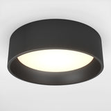 A modern, circular black ceiling light with a wide rim, emitting a soft, even white glow from the center against a plain white background.