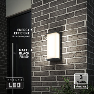 The Artika Faro modern LED indoor-outdoor wall light 3 CCT, with a matte black finish, is mounted on a brick wall. It features energy efficiency, integrated LED (no bulbs needed), and includes a 3-year warranty.