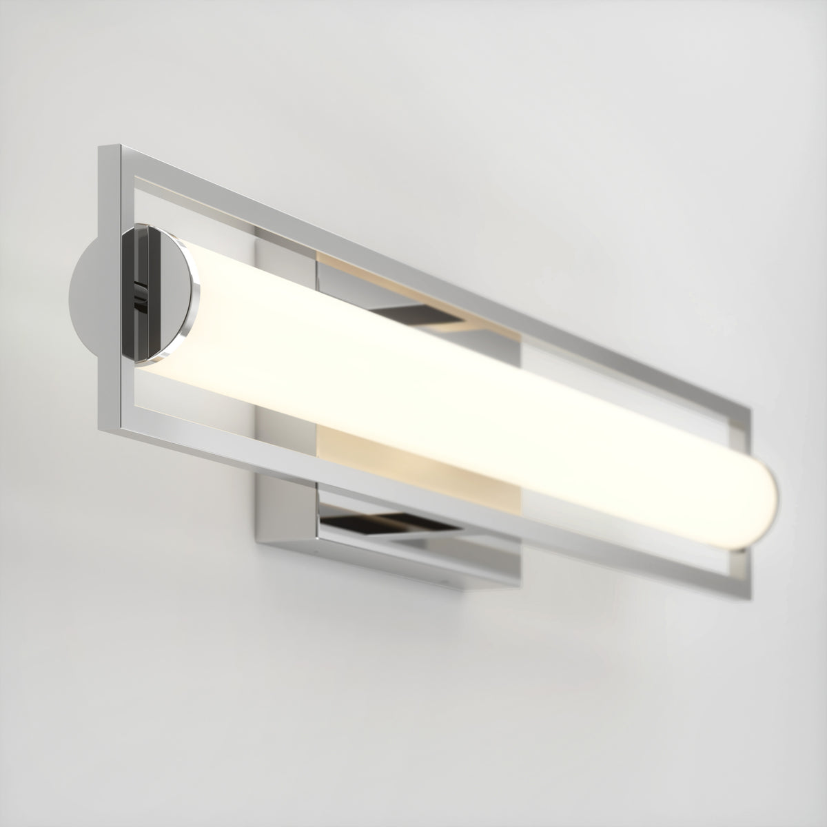 A modern wall-mounted light fixture with a sleek rectangular chrome frame and a cylindrical white frosted glass shade, emitting a soft, even glow against a plain white wall.