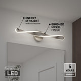 Modern LED wall light with a twisted design mounted above a mirror, featuring brushed nickel finish. Text highlights energy efficiency, no bulbs required, and a 5-year warranty.