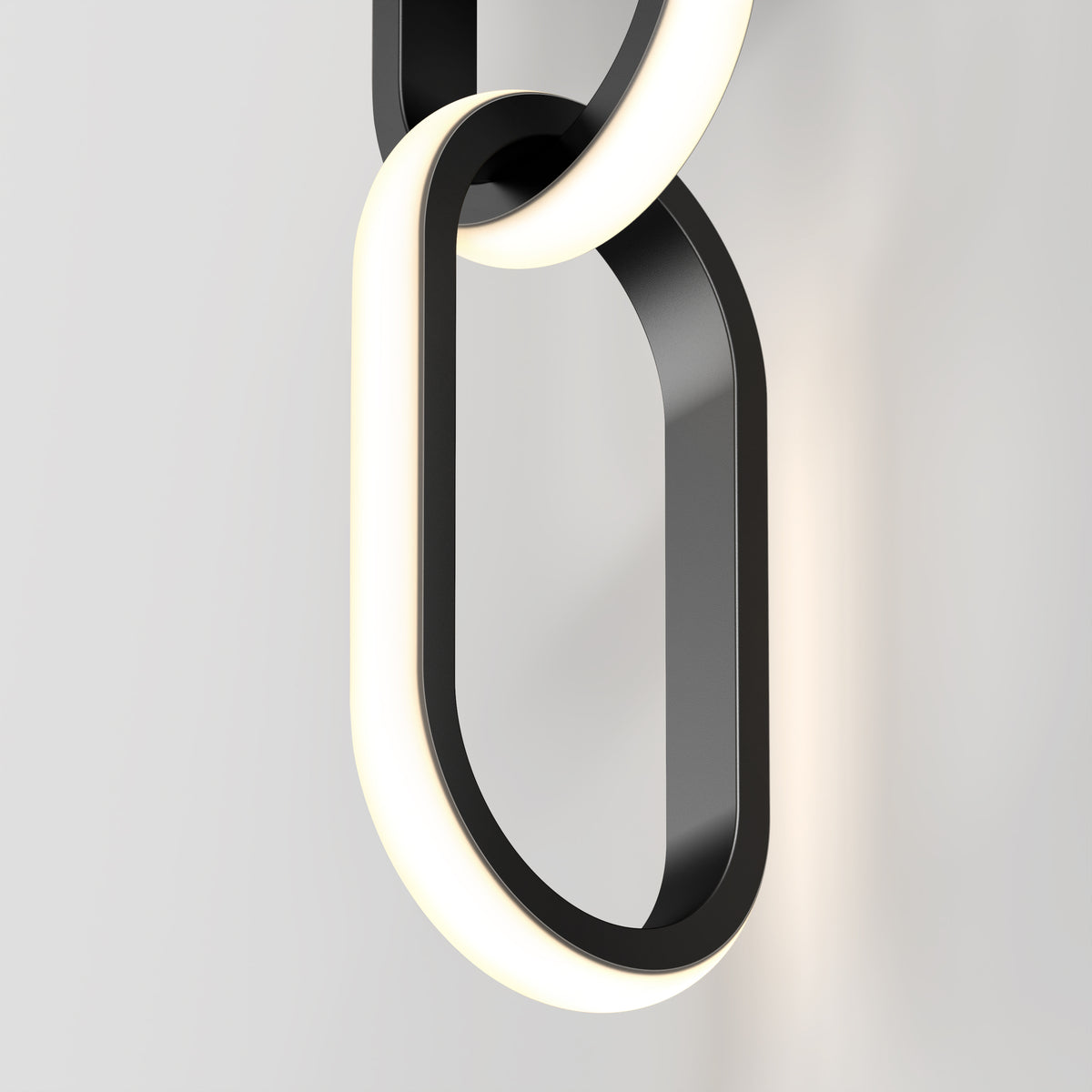 A close-up of modern, black and white illuminated chain links fixed to a light-colored wall, forming a minimalist and sleek decorative light fixture.