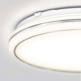 Close-up of the Artika Emina 13 in. LED flush mount light with a smooth white surface and dual glowing rings, installed on a light gray ceiling; features selectable 3 CCT color temperatures.