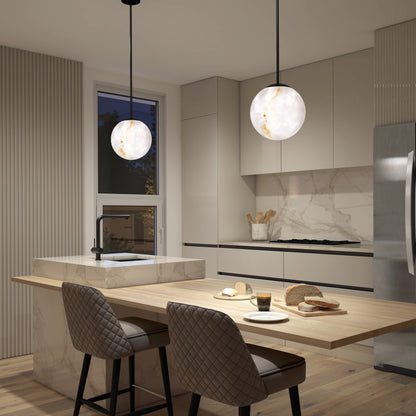 Modern kitchen with marble counters, Selena LED contemporary pendant lights by Artika, beige cabinets, and a wooden island. Two quilted chairs face the island set with bread, cheese, and a glass of dark drink.