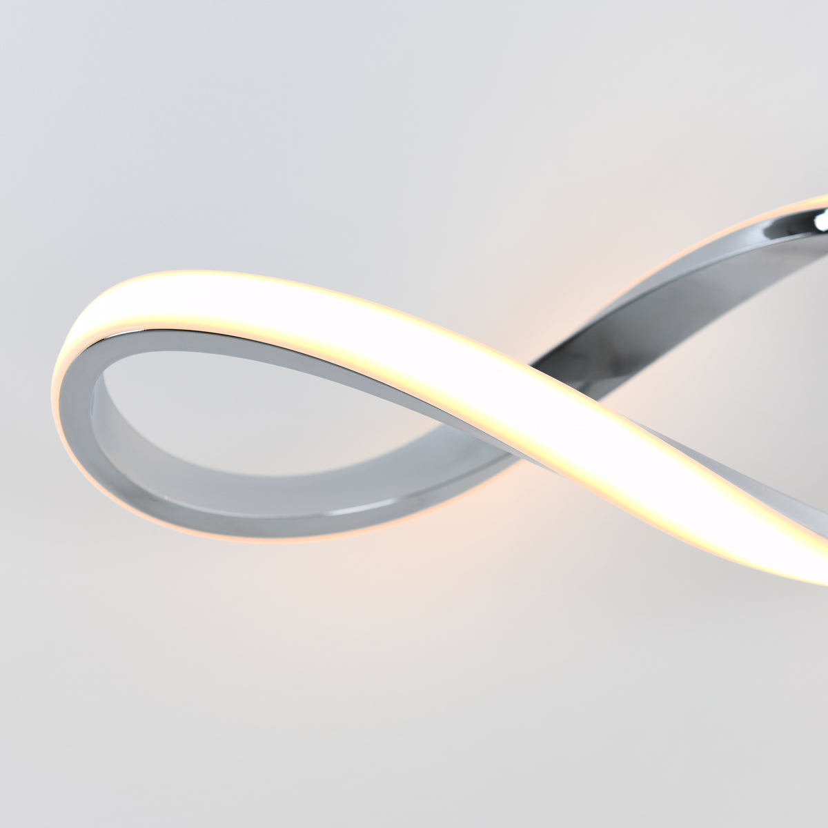 The Artika Swirl modern LED bathroom vanity light features integrated LEDs in an infinity-inspired design with a sleek metallic finish, softly illuminating against a plain white background.
