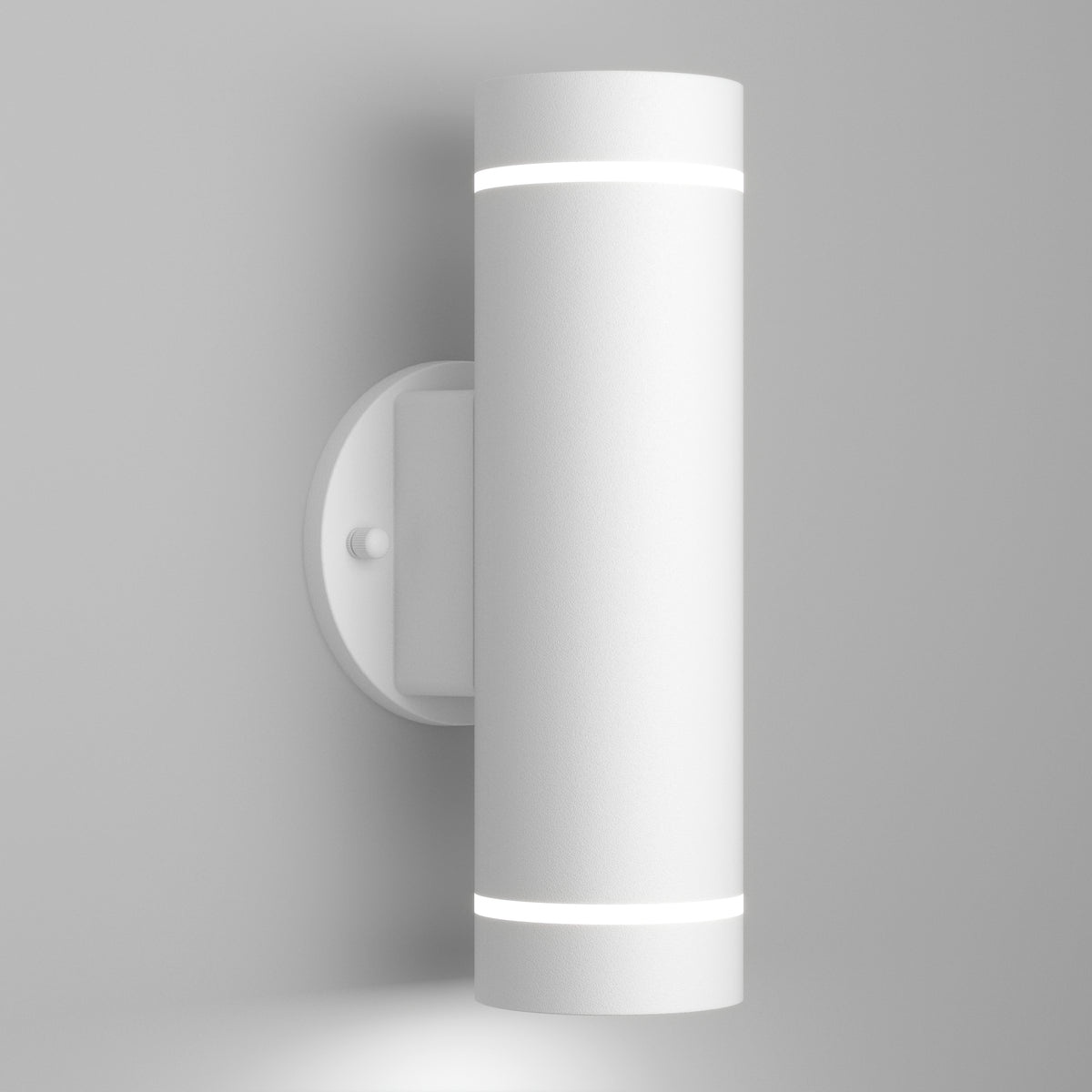 A modern cylindrical white wall sconce emits light from both the top and bottom, mounted on a round base against a plain light gray wall.