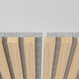 Close-up of two parallel wooden slat panels with a gap between them, mounted on a grey felt backing, against a plain light background.
