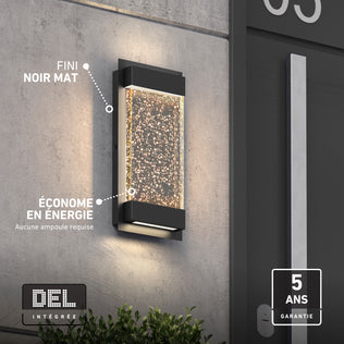 Artika Essence Glow Box LED wall light, black matte, bubble accents, weather-resistant, energy-saving, shown on a gray exterior wall.