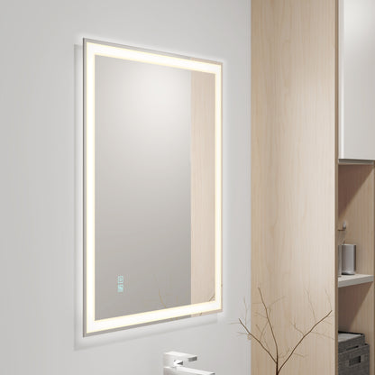 The Artika Sofia LED mirror 3 CCT with defogger is mounted on a white wall above a faucet, accompanied by a light wood cabinet and a decorative branch in a vase.