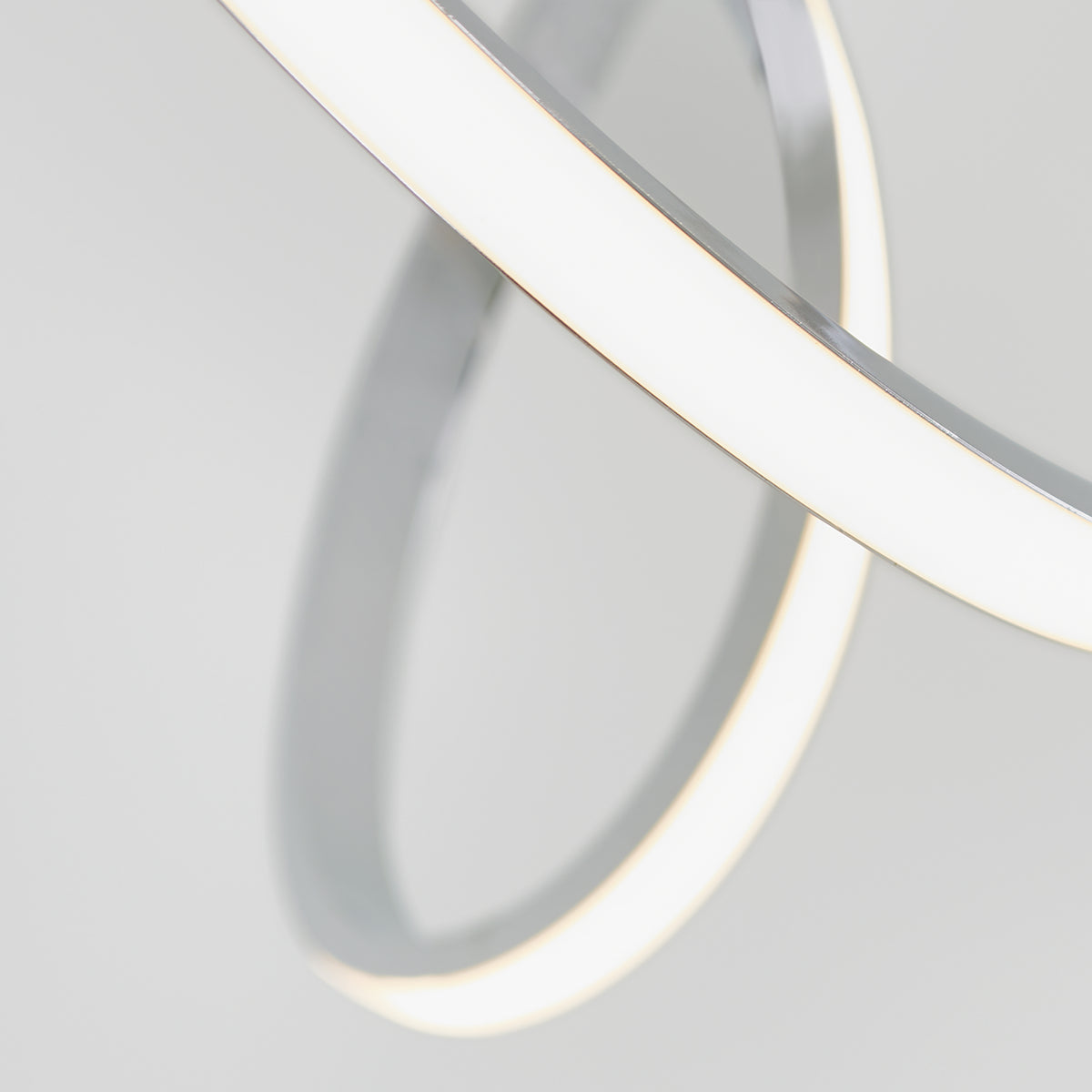 A close-up of two intersecting, white, illuminated rings with a minimalistic design against a light gray background. The rings create a modern and abstract geometric pattern.