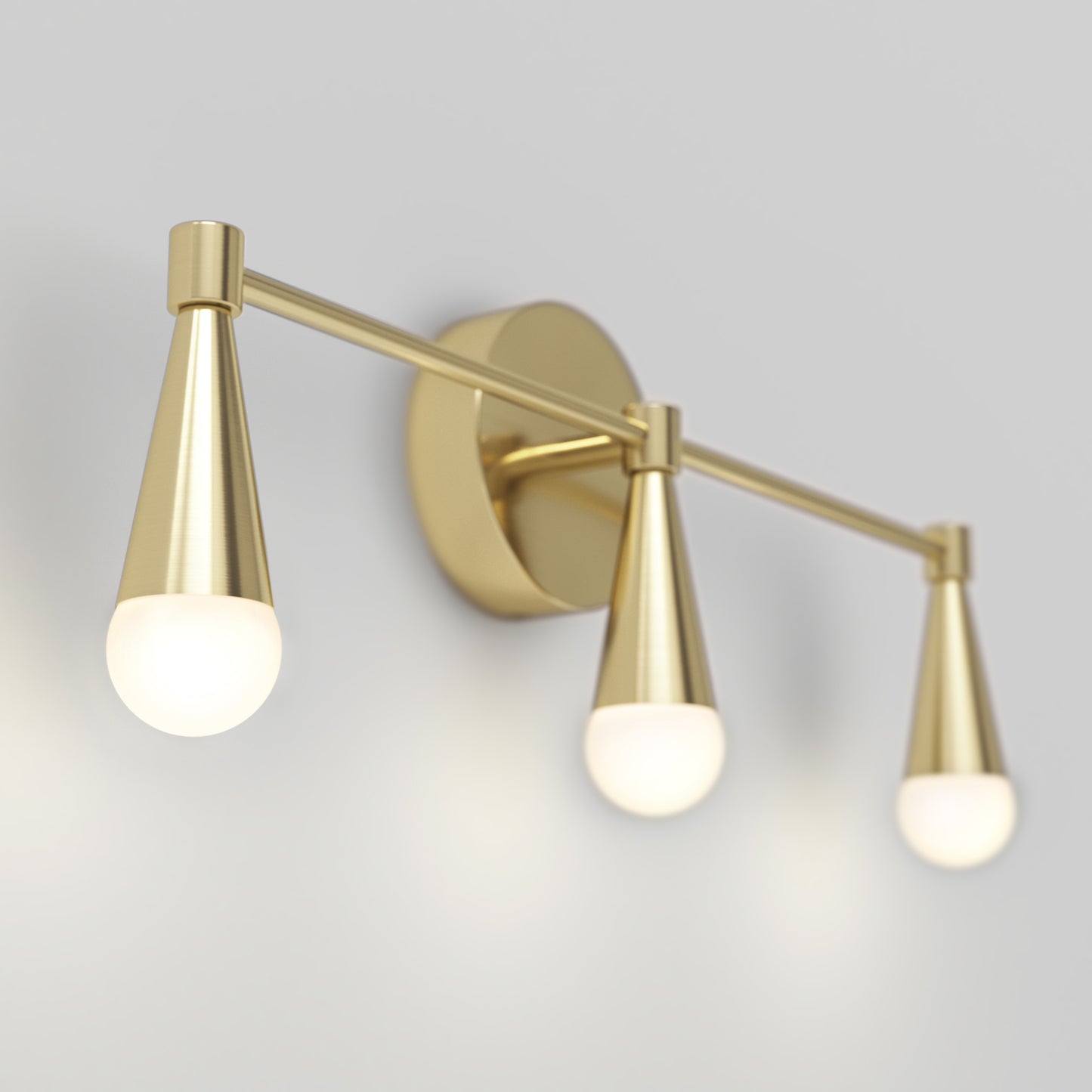 The Artika Wayden LED mid-century bathroom vanity light features three gold cone arms with frosted bulbs on a round gold base, mounted on a light gray wall.