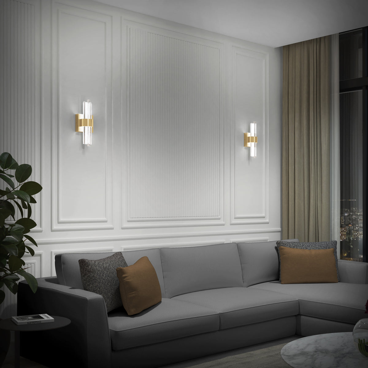 A modern living room features a gray sectional, brown and gray pillows, white paneled walls, a potted plant, beige curtains framing a night city view, and Artika's Dorado contemporary LED wall sconce 3 CCT for luxurious lighting.