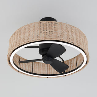 The Artika Kalani 24 in. LED modern ceiling fan has 3 speeds, a remote, black blades, and is housed in a round wicker-style fixture with an integrated circular LED light, mounted on a white ceiling.