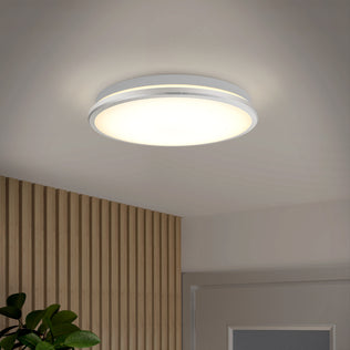 The Artika Vera 13 in. Modern LED Flush Mount Ceiling Light is on, illuminating a room with a wood slat wall, green plant, and white door.