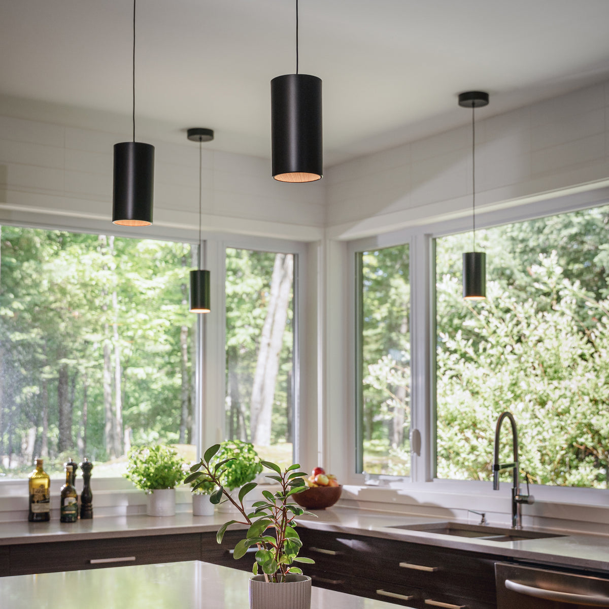 Modern kitchen with Artika Alton mini LED pendant lights (5 CCT), large windows, and a view of greenery outside.