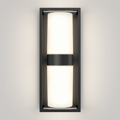 A modern wall sconce with a rectangular black frame and a central horizontal black band, featuring a frosted white cylindrical light emitting a soft glow against a light-colored wall.