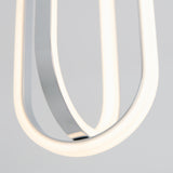 A close-up of a modern light fixture featuring curved, glowing white LED tubes and reflective metal elements against a soft, neutral background.