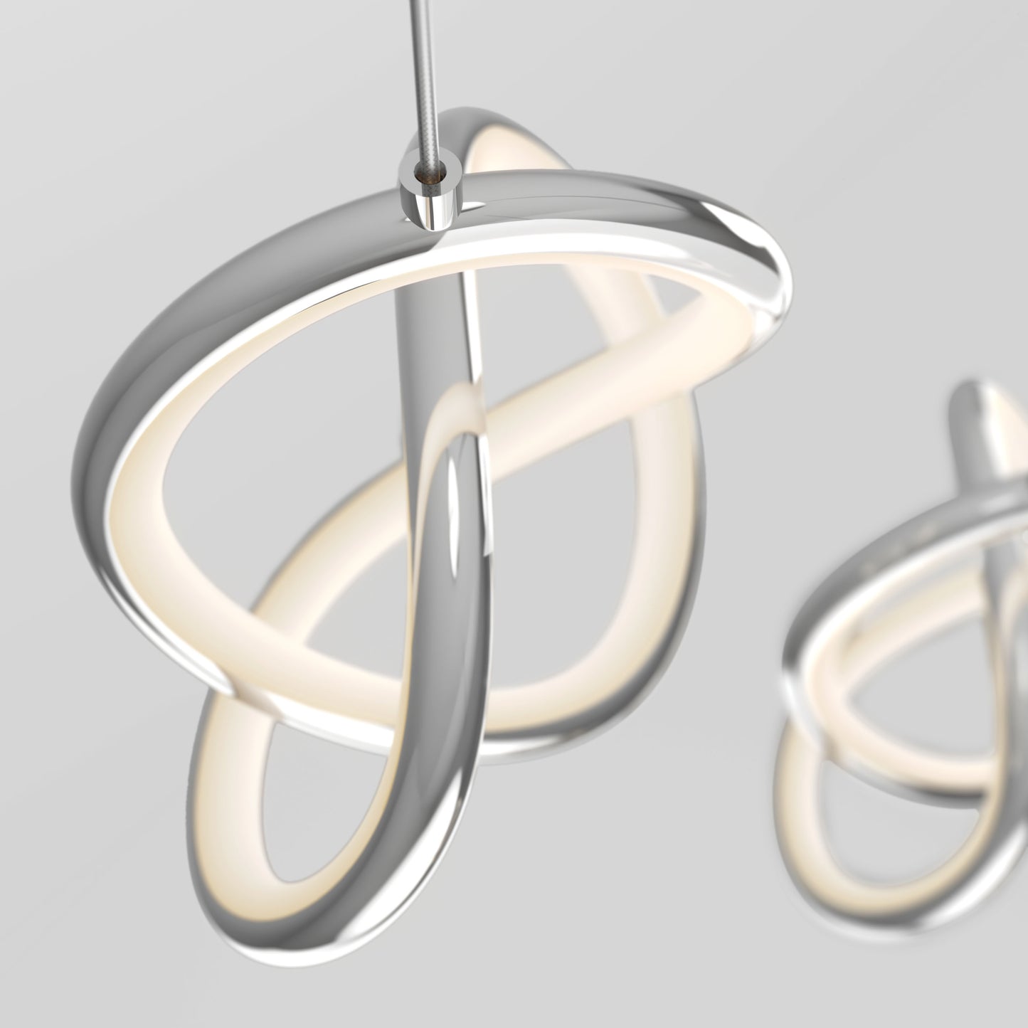 The Artika Zephyr 3-light LED pendant features intertwined metallic loops and built-in LEDs, suspended by a thin wire against a light gray background, with another similar fixture partially visible behind it.